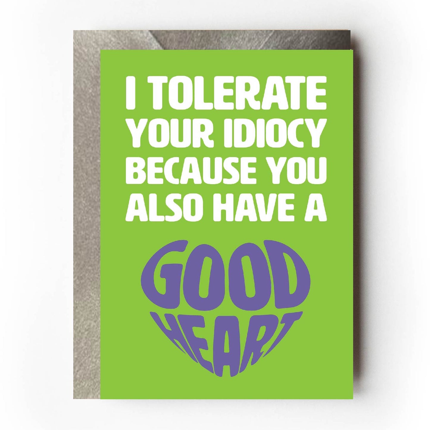 Text on card is white and purple against a green background and states "I tolerate your idiocy because you also have a good heart" Card measures 105 x 150mm and is supplied with a very striking pewter-effect eco-Kraft envelope.