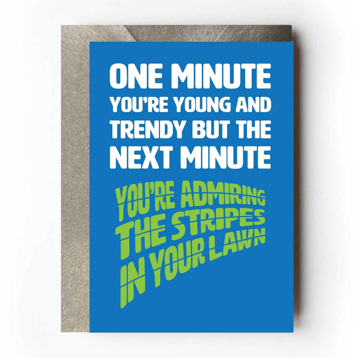 Text on card is white and green against a blue background and states "One minute you're young and trendy but the next minute you're admiring the stripes in your lawn" Card measures 105 x 150mm and is supplied with a very striking pewter-effect eco-Kraft envelope.