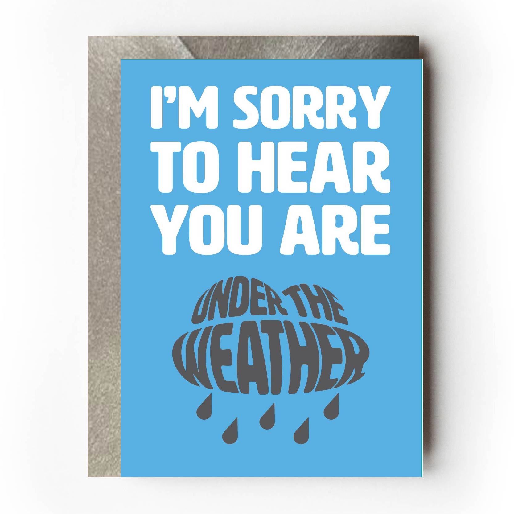 Text on card is white and grey against a light blue background and states "I'm sorry to hear"  In the shape of a rain with rain beneath it, further text then states "You're under the weather"  Card measures 105 x 150mm and is supplied with a very striking pewter-effect eco-Kraft envelope.