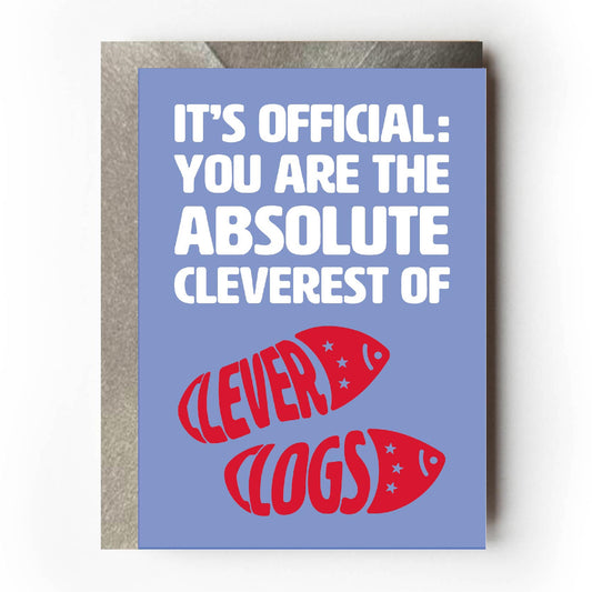 Text on card is white and red against a purple background and states "It's official: you are the absolute cleverest of clever clogs"  The red clever clog text is in the shape of a pair of clogs.  Card measures 105 x 150mm and is supplied with a very striking pewter-effect eco-Kraft envelope.