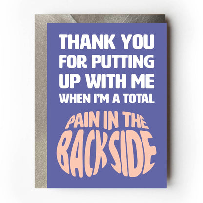 Text on card is white and peach against a purple background and states "Thank you for putting up with me when I'm a total pain in the backside"  The text 'pain in the backside' is shaped like a bottom"  Card measures 105 x 150mm and is supplied with a very striking pewter-effect eco-Kraft envelope.