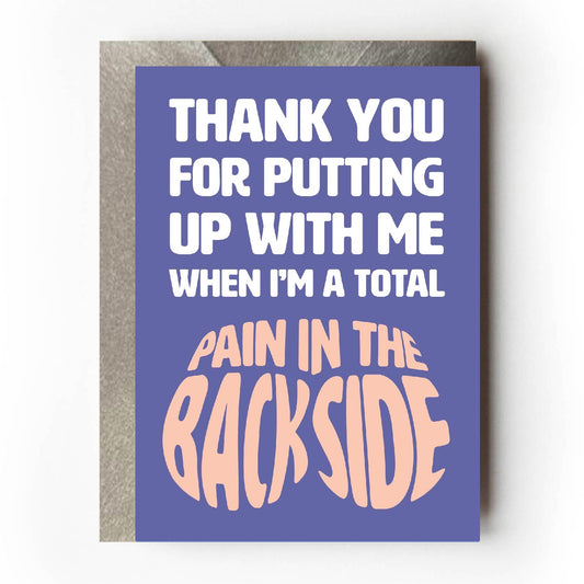 Text on card is white and peach against a purple background and states "Thank you for putting up with me when I'm a total pain in the backside"  The text 'pain in the backside' is shaped like a bottom"  Card measures 105 x 150mm and is supplied with a very striking pewter-effect eco-Kraft envelope.