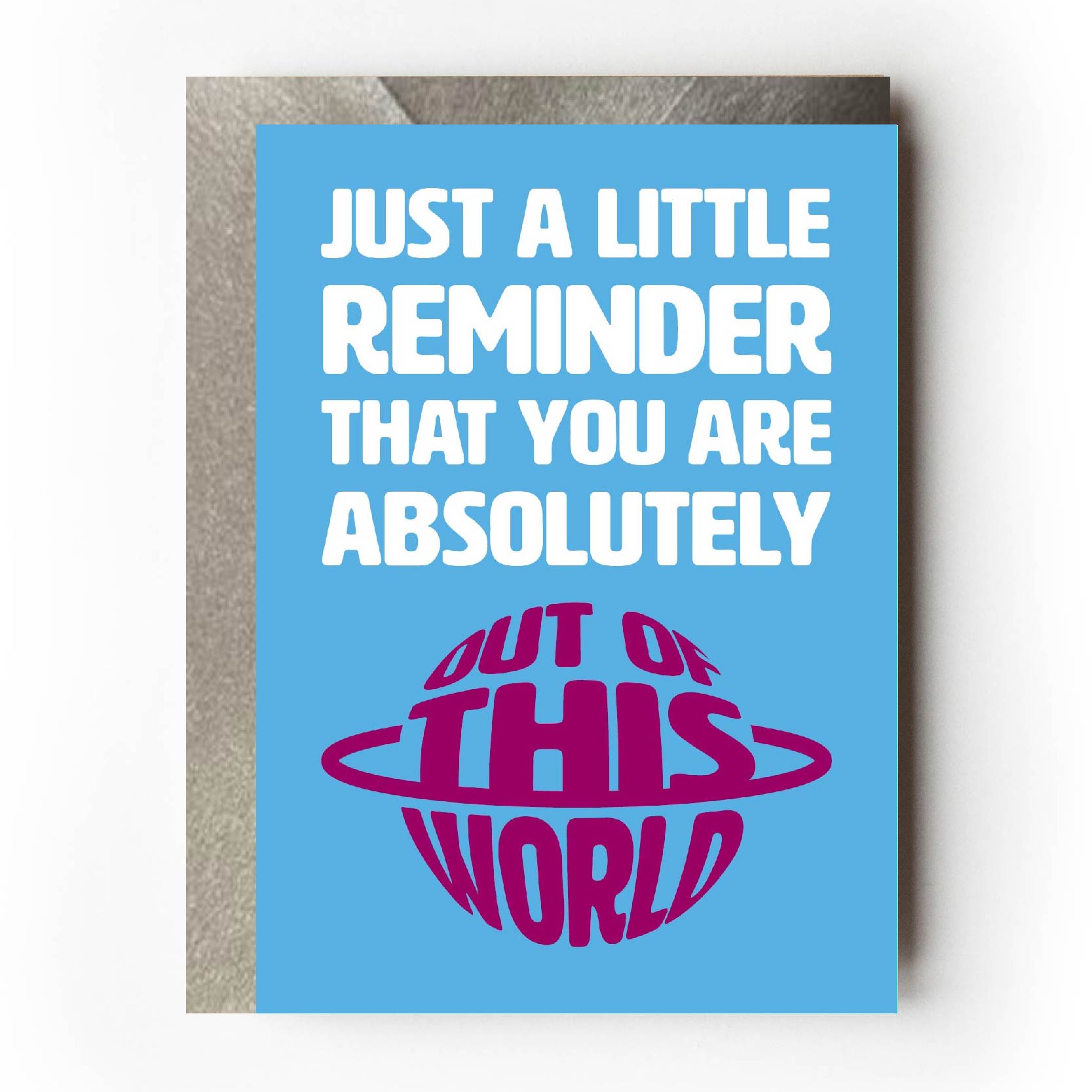 Text on card is white and burgundy against a light blue background and states "Just a little reminder that you are absolutely out of this world"  The out of this world text is in the shape of a planet with rings around it.  Card measures 105 x 150mm and is supplied with a very striking pewter-effect eco-Kraft envelope.