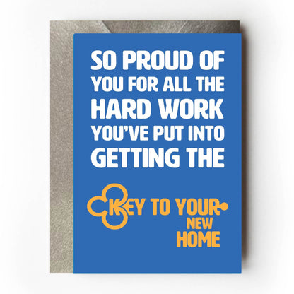 Text on card is white and yellow against a blue background and states "So proud of you for all the hard work you've put into getting the key to your new home"   The text which states 'key to your new home' is in the shape of a key  Card measures 105 x 150mm and is supplied with a very striking pewter-effect eco-Kraft envelope.