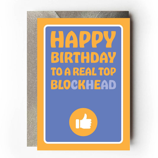Greeting card with 'Happy Birthday to a Real Top Blockhead' (with BLOKE highlighted) text on a purple background with yellow border