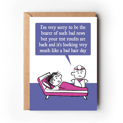 Cartoon doctor stands at the bedside of a patient lying in bed with messy hair. The doctor states "I'm very sorry to be the bearer of such bad news but your test results are back and it's looking very much like a bad hair day" Card is purple, pink and white. 
