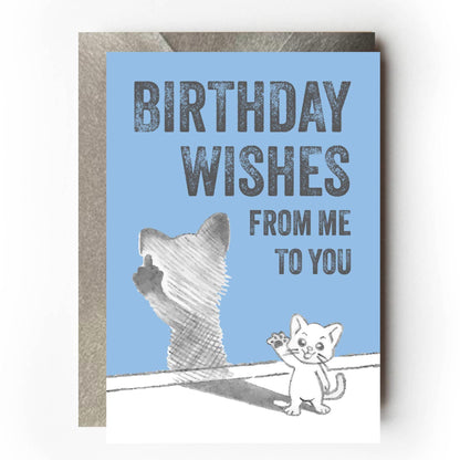 Happy cat waving at you while its shadow is flicking the bird and giving the one finger salute. Text reads: “Birthday wishes from me to you” Funny sarcastic birthday card design for cat lovers.